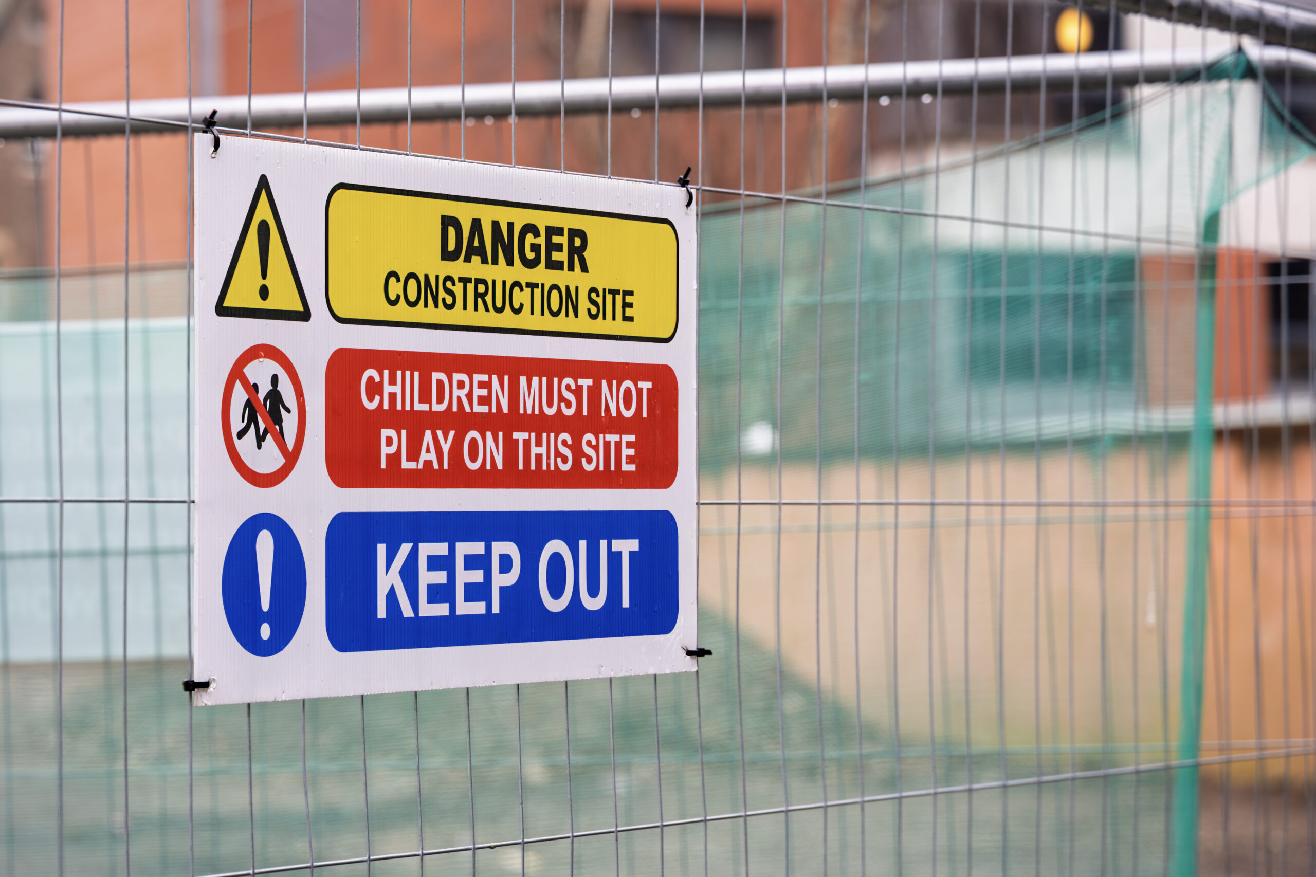 Branding & Signage Guides: Construction safety sign on Heras fencing displaying warnings including Danger Construction Site, Children Must Not Play, and Keep Out